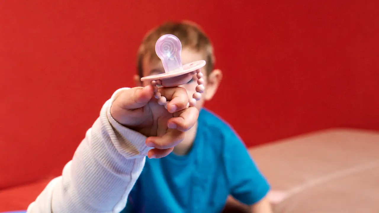 Un enfant tient une sucette propre dont la téterelle et la collerette sont visibles