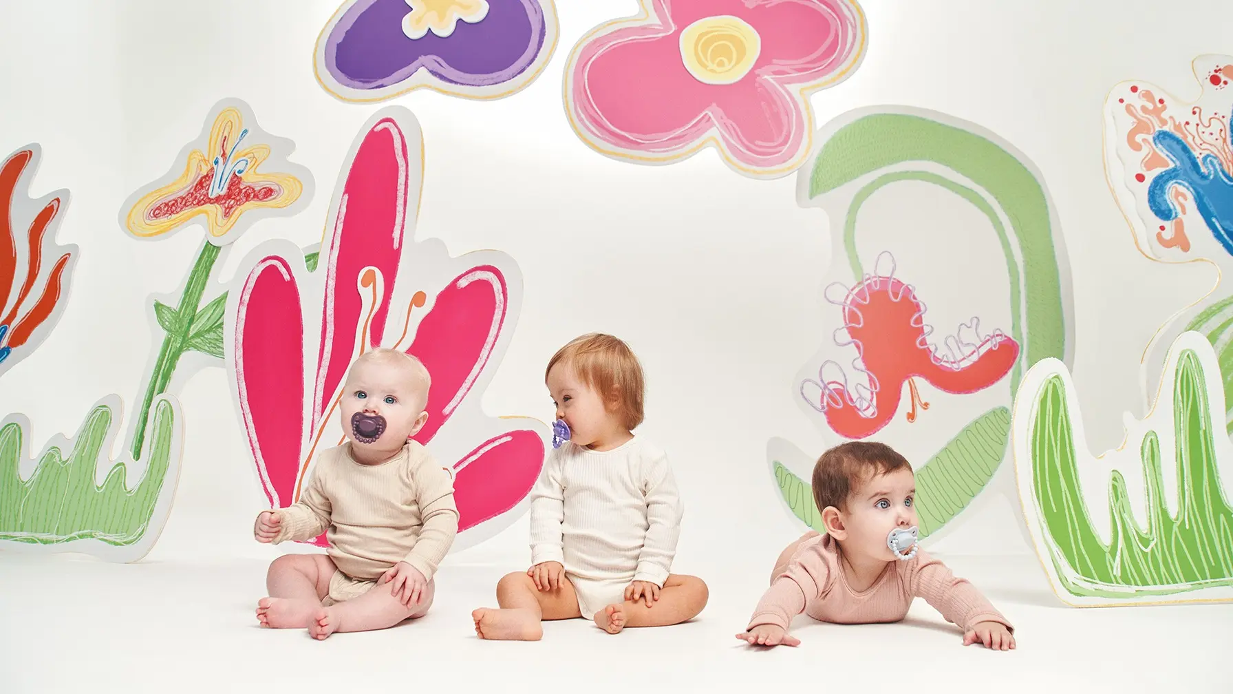 Trois bébés d’âges différents avec des sucettes, illustrant le choix de la taille selon l’âge